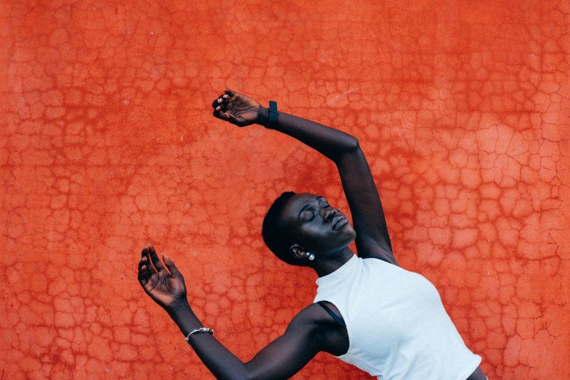 Beautiful black girl standing in front of an orange wall.